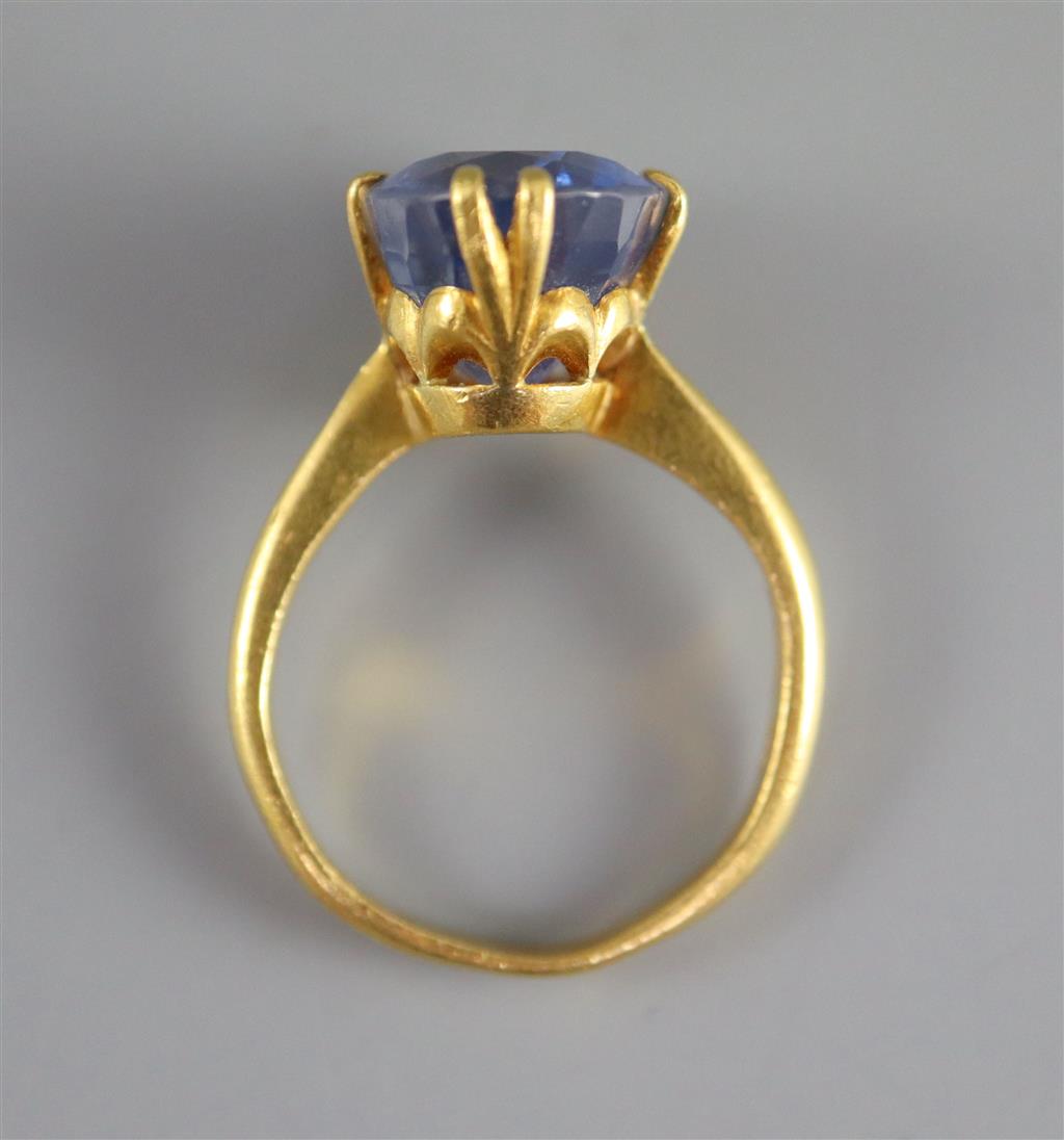 A gold (stamped 24k) and solitaire oval cut Ceylon sapphire set ring,